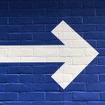 white arrow painted on brick wall